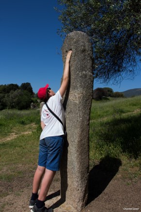 Photo de Matthieu qui tente de toucher le haut d'un menhir sur le site mégalithique de Filitosa