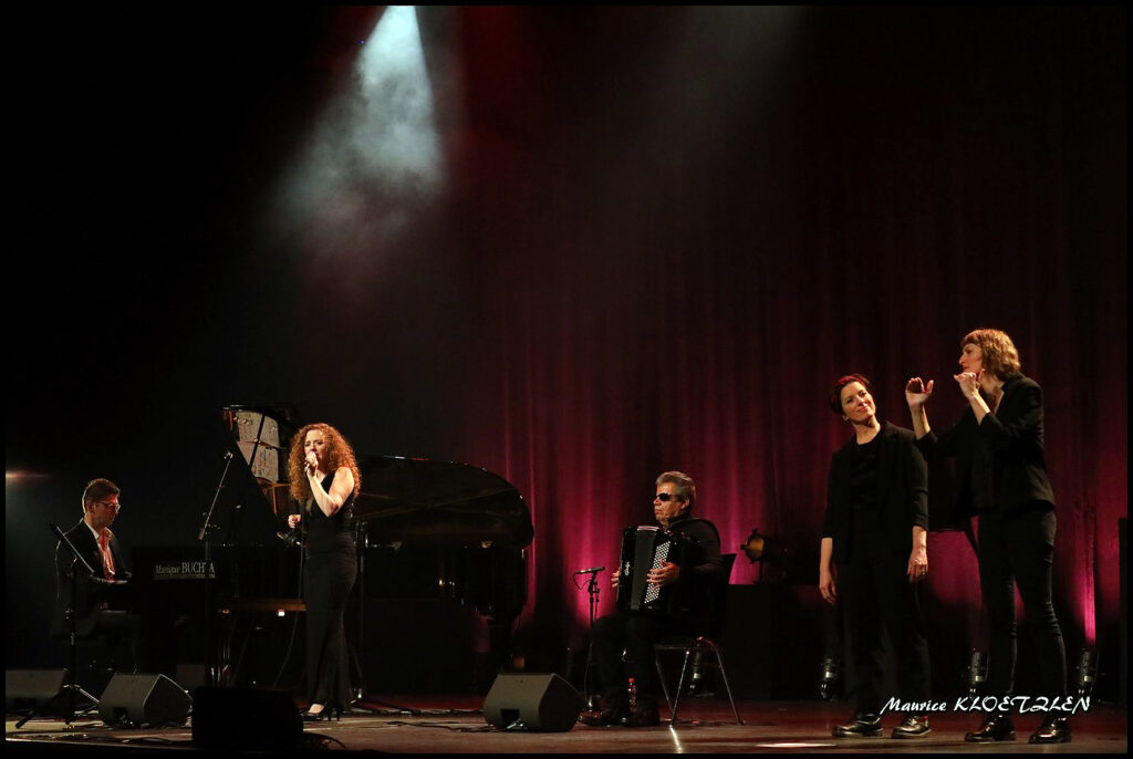 Photo de la scène avec Grégory Ott au piano, Marikala au chant, Marcel Loeffler à l'accordéon et Rachel et Séverine à la traduction en langue des signes