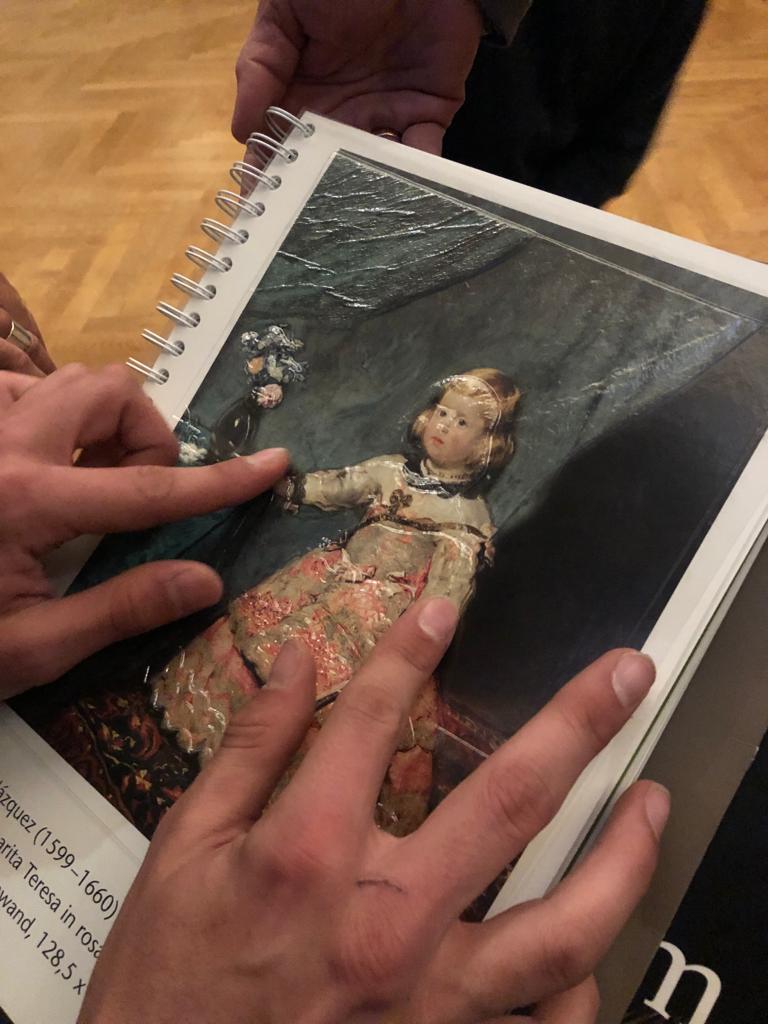 Des mains touchent une oeuvre en relief du musée des beaux-arts