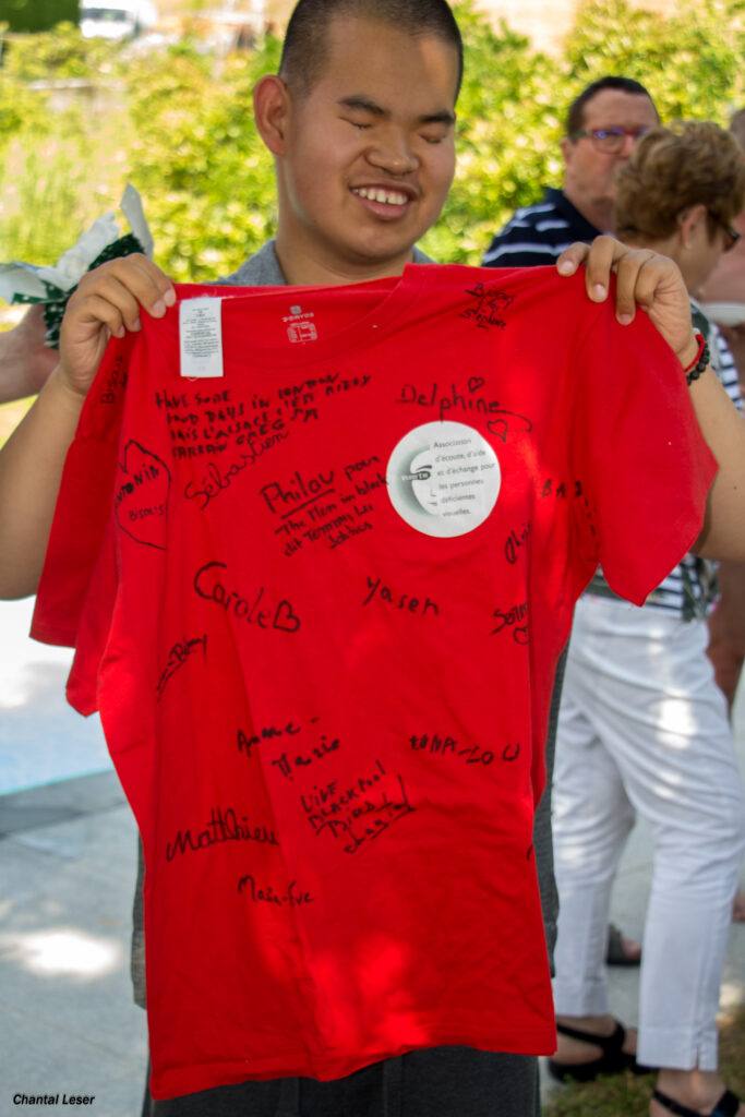 Tom montre son tee-shirt souvenir offert et signé par tous les participants qu'il emmènera avec son déménagement en Angleterre