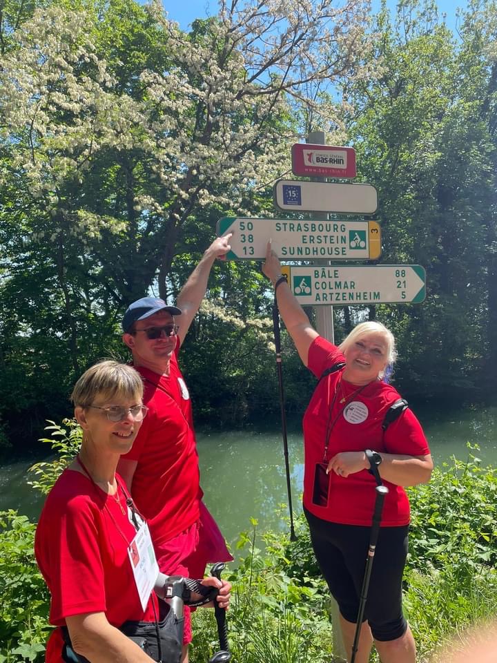 Rachel, Sébastien et Valérie montrent le panneau sur lequel est indiqué qu'il y a 50 km jusqu'à Strasbourg