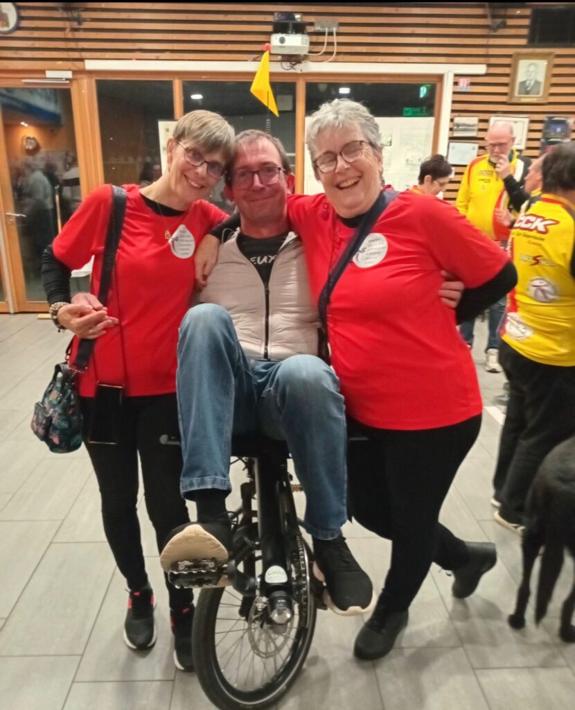 Rachel et Dominique entourent Sébastien assis sur le vélo adapté.