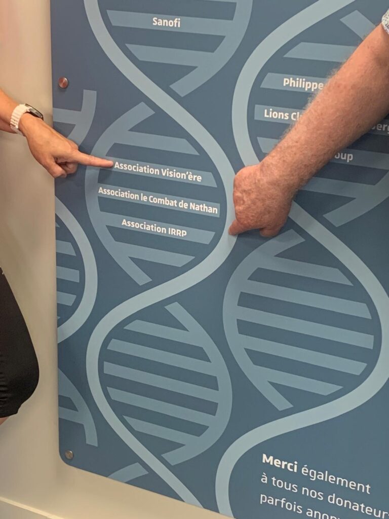 Photo du mur des mécènes en gros plan avec des doigts qui pointent vers l'association Vision'ère et l'association IRRP