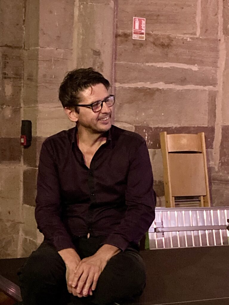 Grégory Ott assis sur l'estrade en train d'écouter le public lui chanter joyeux anniversaire