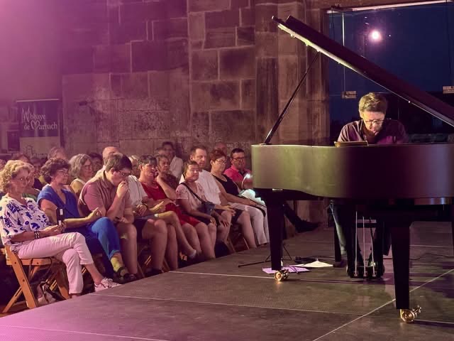 Photo de Grégory Ott au piano avec en arrière plan le public dont tous les Vision'ère au premier rang