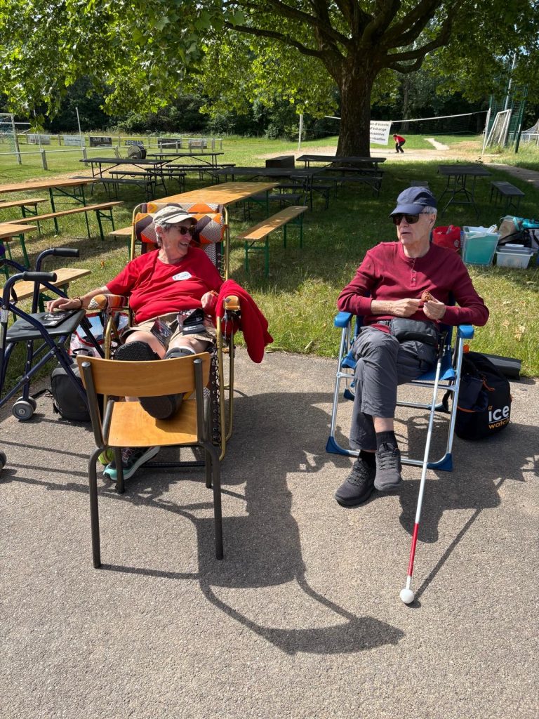 Chantal installée dans son fauteuil avec sa cheville dans sa botte et en hauteur en discussion avec Hubert assis à ses côtés