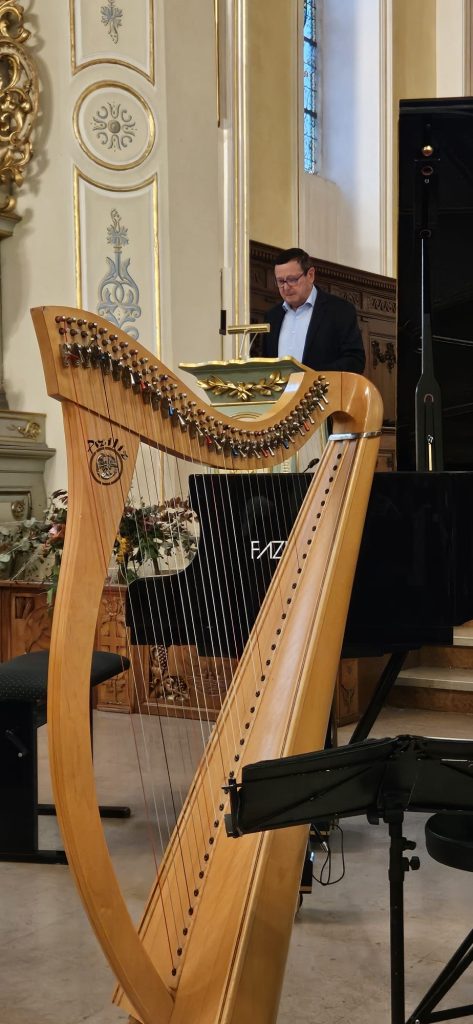 Jean-Rémy au pupitre pour son discours d'accueil avec le piano et la harpe en premier plan